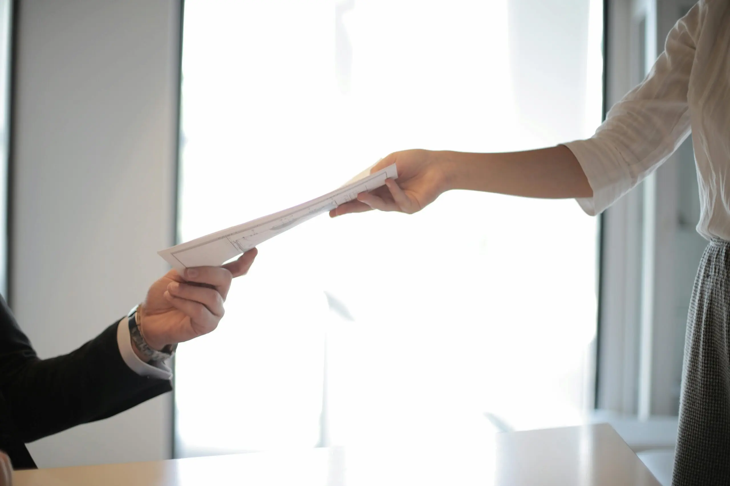 Deux personnes qui se tendent un document